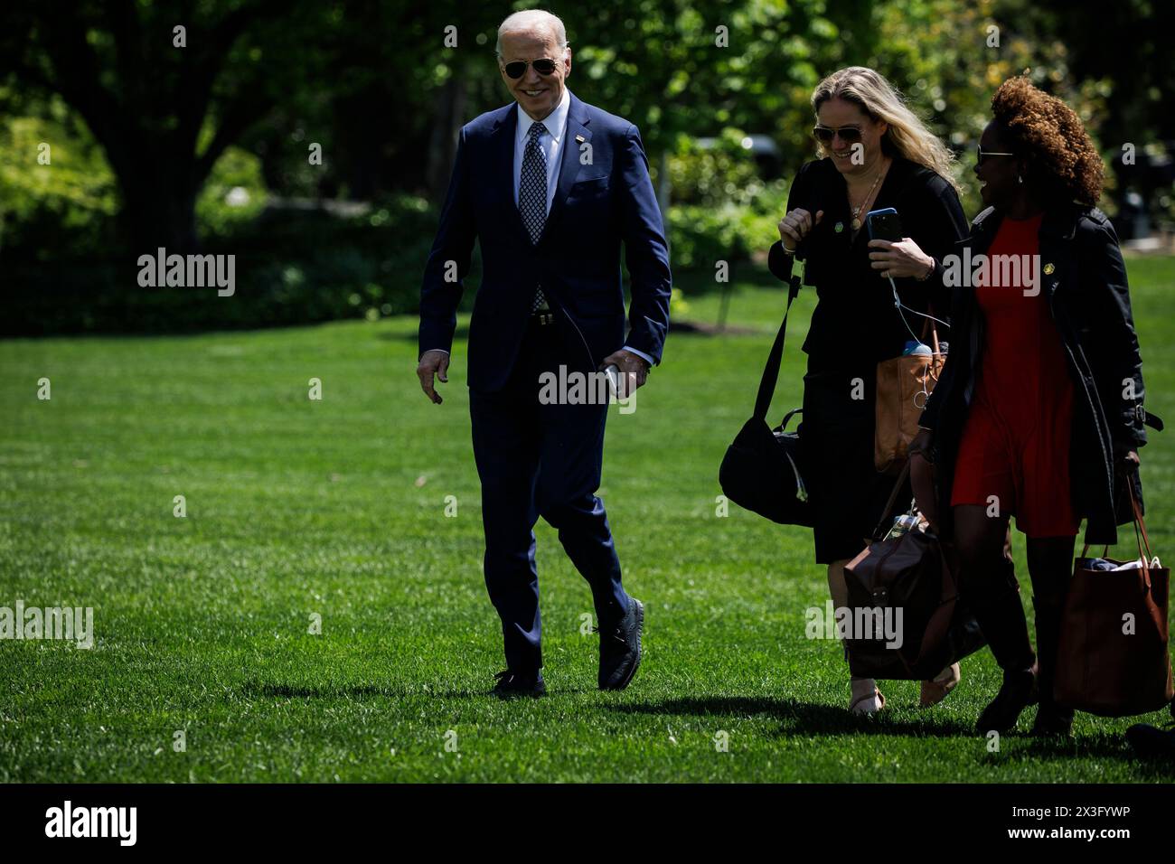 Washington, DC. 26 aprile 2024. Il presidente degli Stati Uniti Joe Biden attraversa il South Lawn con il segretario alla stampa della Casa Bianca Karine Jean-Pierre (a destra) e il vice capo di stato maggiore Annie Tomasini (al centro) verso la Casa Bianca il 26 aprile 2024 a Washington, DC. Il presidente Biden ha detto che hes è disposto a discutere l'ex presidente Donald Trump, che è il presunto candidato presidenziale repubblicano, durante un'intervista con Howard Stern questa mattina. Credito: Samuel Corum/Pool tramite CNP/dpa/Alamy Live News Foto Stock