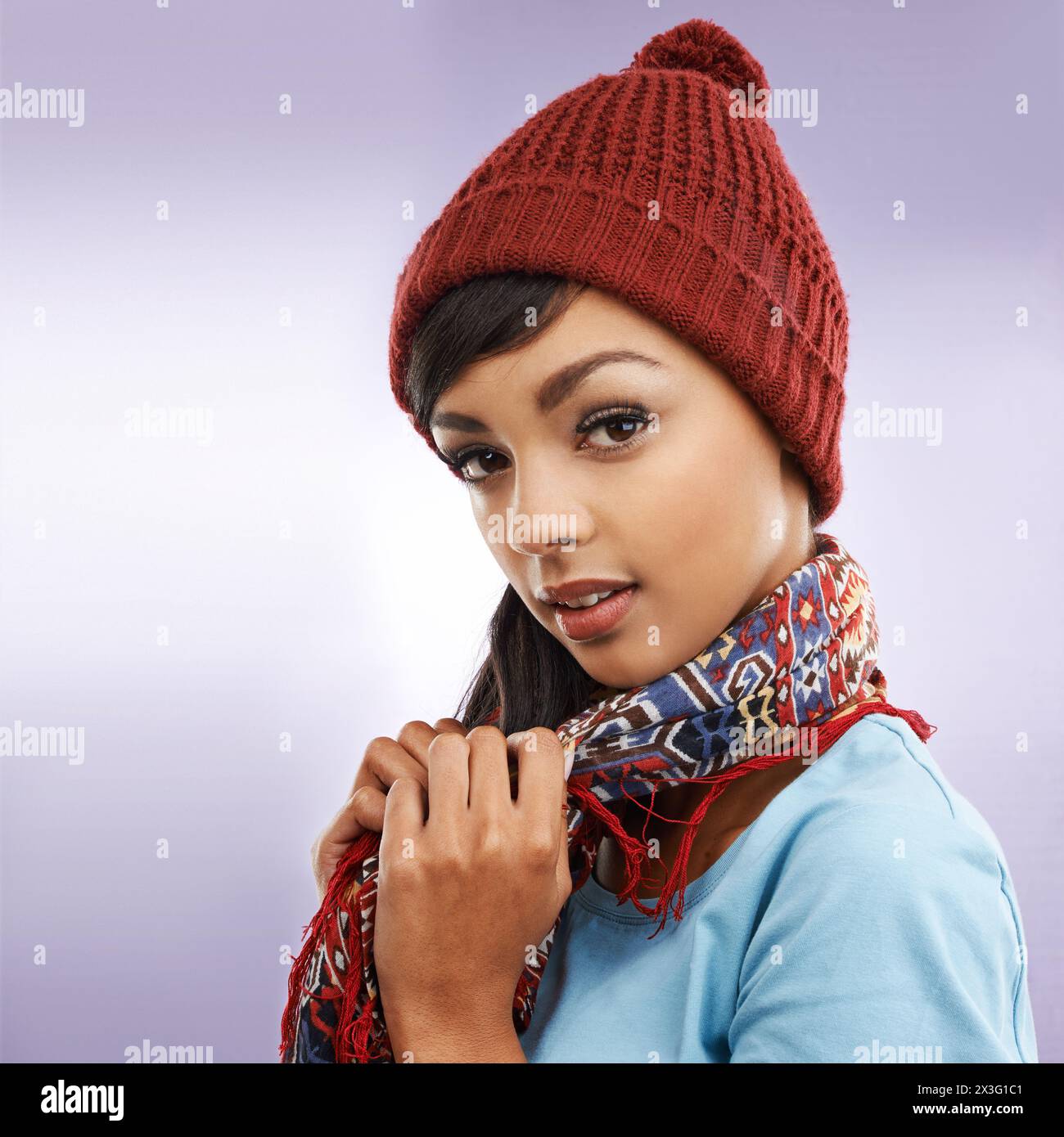 Moda, donna e ritratto in inverno, studio e berretto per uno sfondo caldo e colorato. Accessori, abbigliamento o capsula con stile per il freddo Foto Stock