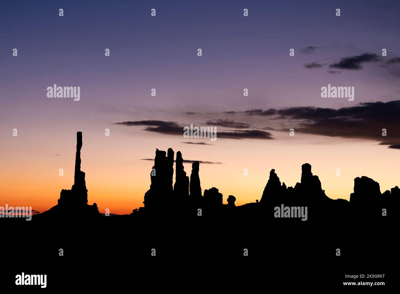 Alba dietro il famoso totem pole della Monument Valley e le vicine guglie, tutte formate da milioni di anni di erosione causata dal vento e dalla pioggia. Foto Stock