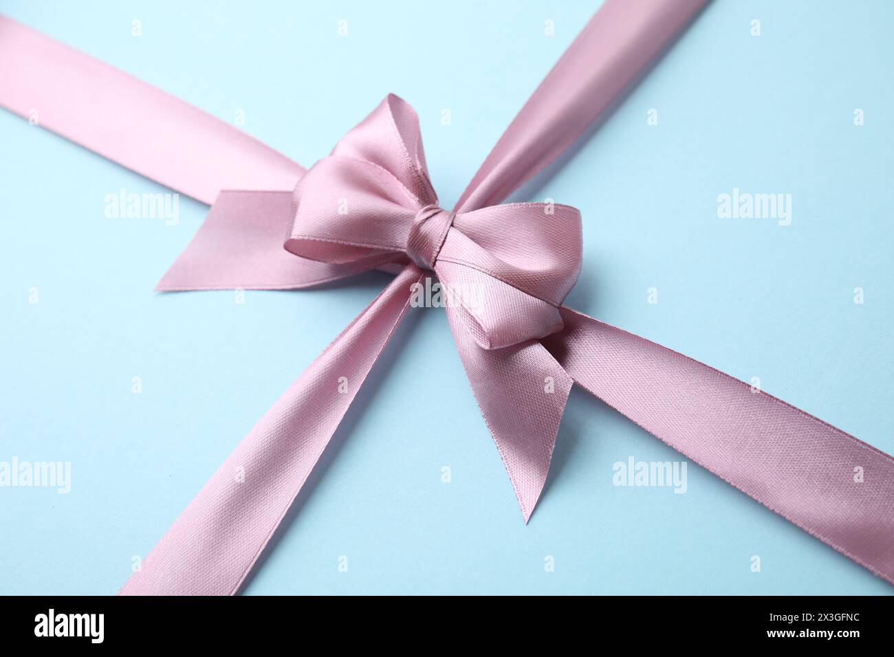 Nastro in raso rosa con fiocco su sfondo azzurro, primo piano Foto Stock