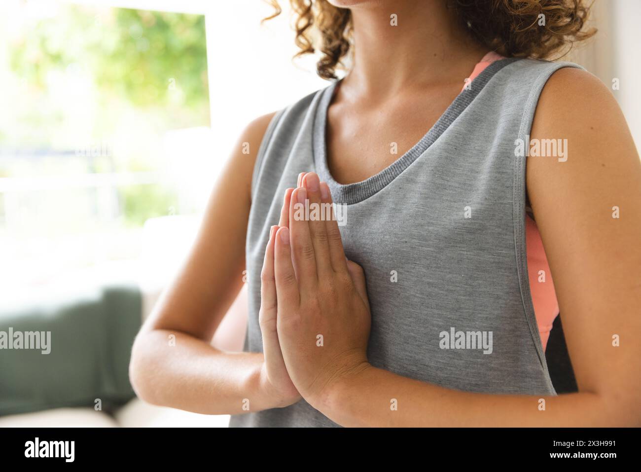 Una giovane donna caucasica con capelli ricci castani che pratica yoga a casa Foto Stock