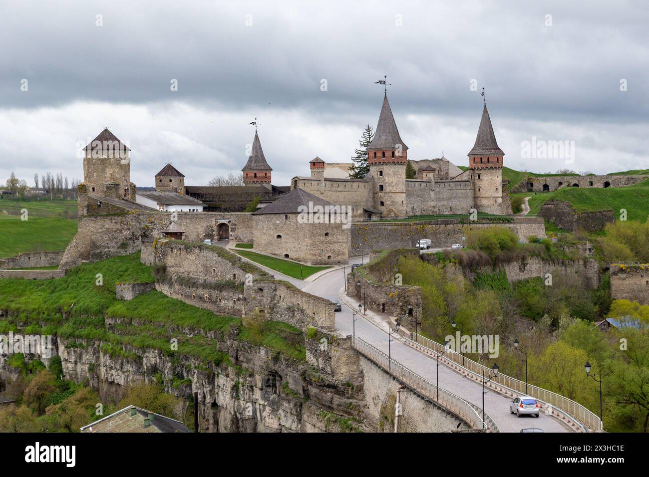 KAMENETS-PODOLSKY, UCRAINA - 26 APRILE 2023: Questa è una vista del ponte del castello e del castello medievale in una serata primaverile nuvolosa. Foto Stock