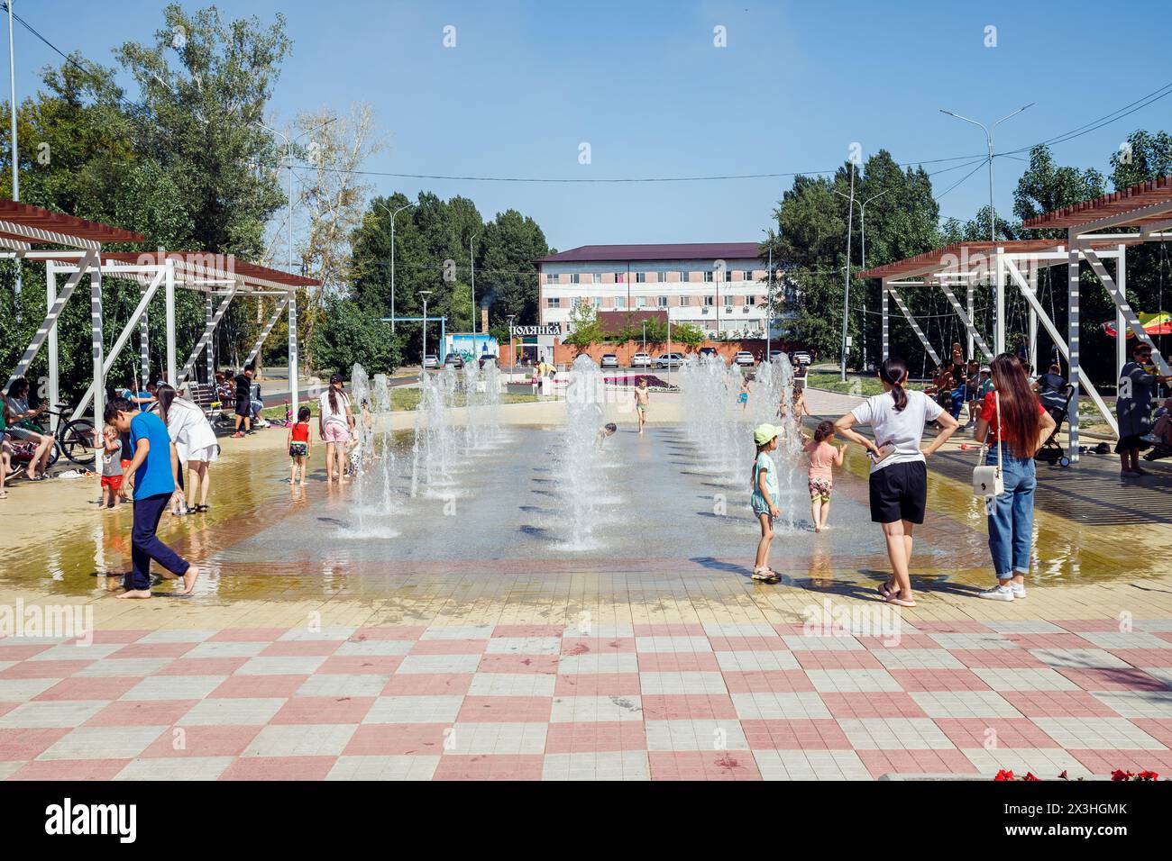 bambini e adulti nella fontana della città nelle calde giornate di sole. freschezza in calore. bambini e adulti si rinfrescano nella fontana della città nel parco urbano di Foto Stock