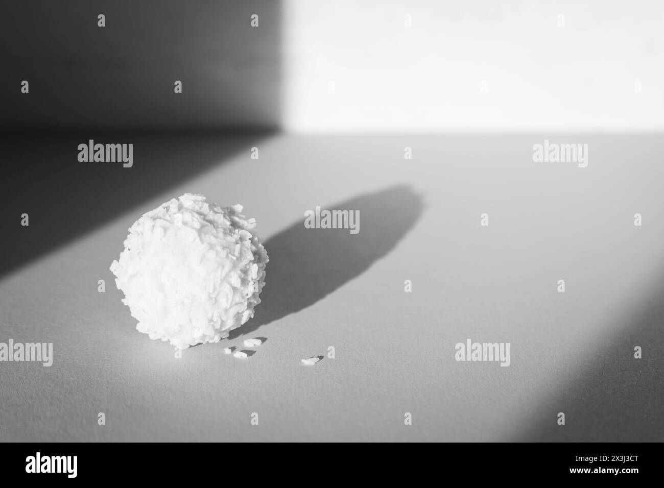 Caramelle cremose, monocromatiche. cocco raffaello alla luce del sole, bianco e nero. Concetto di semplicità. Dolce dolce isolato. Caramelle praline al sole. Foto Stock