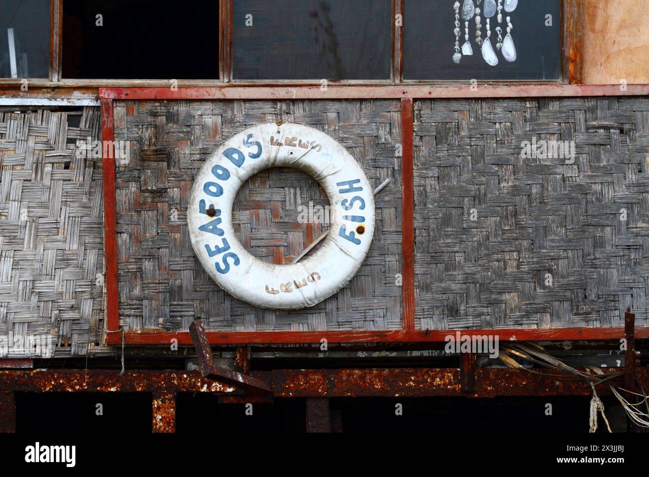 Vecchia cintura di salvataggio con scritto "pesce fresco di mare" appeso su una parete di mattoni di bambù del ristorante vicino al porto dei pescatori di Arica, Cile Foto Stock