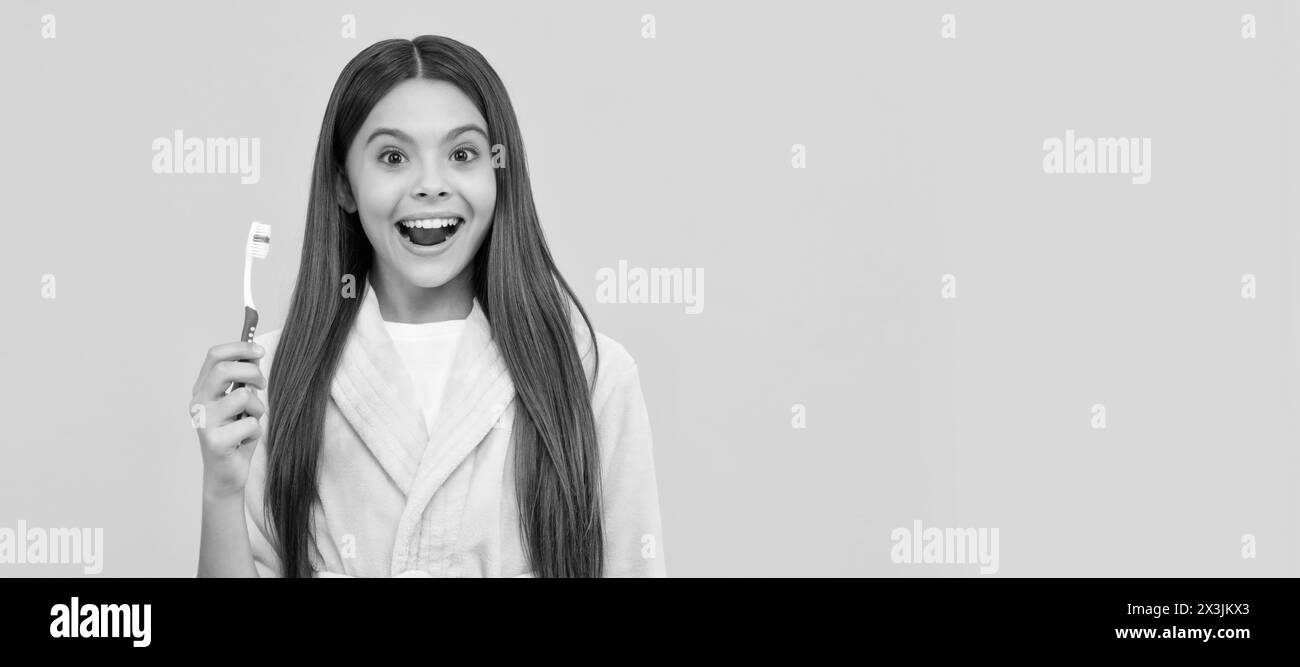 sorpresa ragazza adolescente in casa terry accappatoio tenere spazzolino da denti, la cura della bocca. Banner di bambina con pennello denti, ritratto studio, intestazione con spazio copia Foto Stock