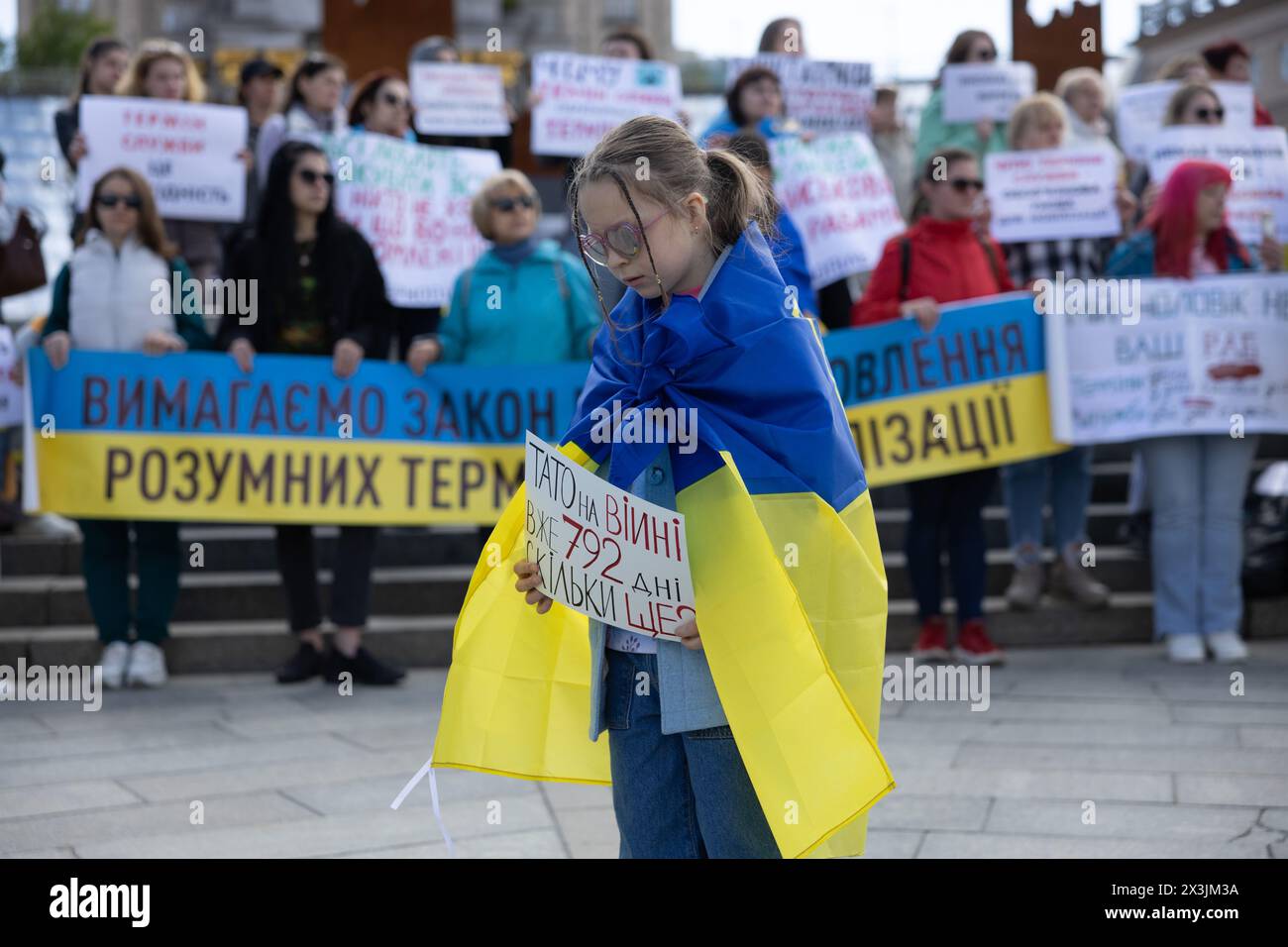 Kiev, Ucraina. 27 aprile 2024. Una ragazza ha un cartello che dice: "Papà è già in guerra da 792 giorni. Quanto ancora?" Mentre prende parte a un raduno che chiede l'istituzione di termini di smobilitazione, presso la Piazza dell'indipendenza a Kiev. La gente si riunì per chiedere i termini di durata del servizio nell'esercito, di essere in prima linea, e di una rotazione equa. Le condizioni di smobilitazione non sono previste da una nuova legge sulla mobilitazione adottata dal Parlamento ucraino e firmata di recente dal Presidente Zelensky. Crediti: SOPA Images Limited/Alamy Live News crediti: SOPA Images Limited/Alamy Live News Foto Stock