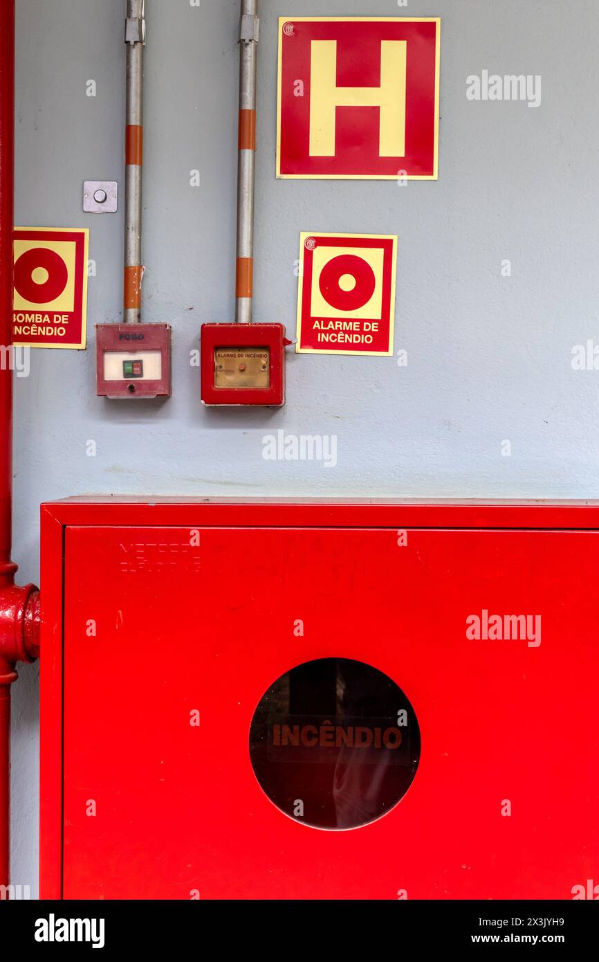 Dettaglio di un idrante antincendio e di un allarme per estinguere e prevenire gli incendi, con opportuni cartelli in portoghese Foto Stock