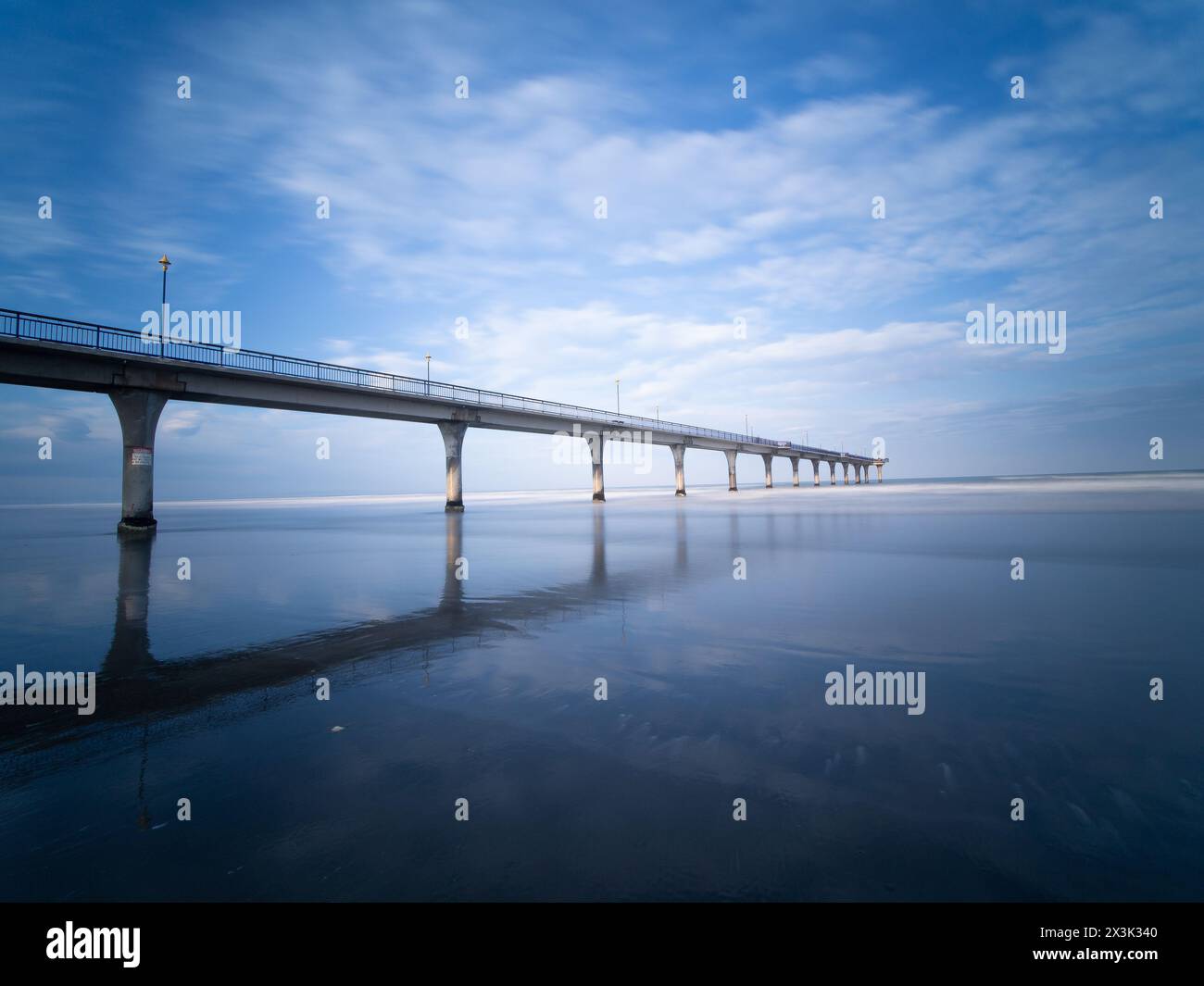 Assisti all'ipnotico tramonto dell'ora blu mentre passeggi lungo l'incantevole ponte di New Brighton a Christchurch, nuova Zelanda Foto Stock