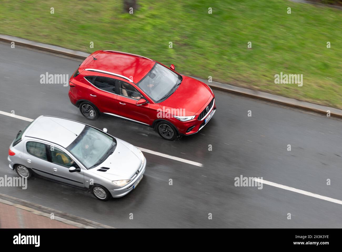 OSTRAVA, REPUBBLICA CECA - 23 MARZO 2024: Crossover cinese rosso MG ZS che sorpassa l'auto Peugeot 206 in forte pioggia su strada Foto Stock