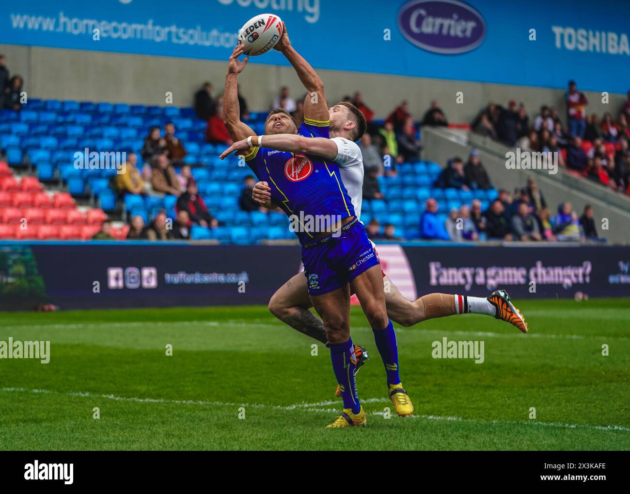 Salford, Manchester, Regno Unito. 27 aprile 2024. Super League Rugby: Salford Red Devils vs Warrington Wolves al Salford Community Stadium. ETHAN RYAN fa il tackle sul giocatore dei Warrington MATTY RUSSELL mentre entrambi sfidano per la palla. Credito James Giblin/Alamy Live News. Foto Stock