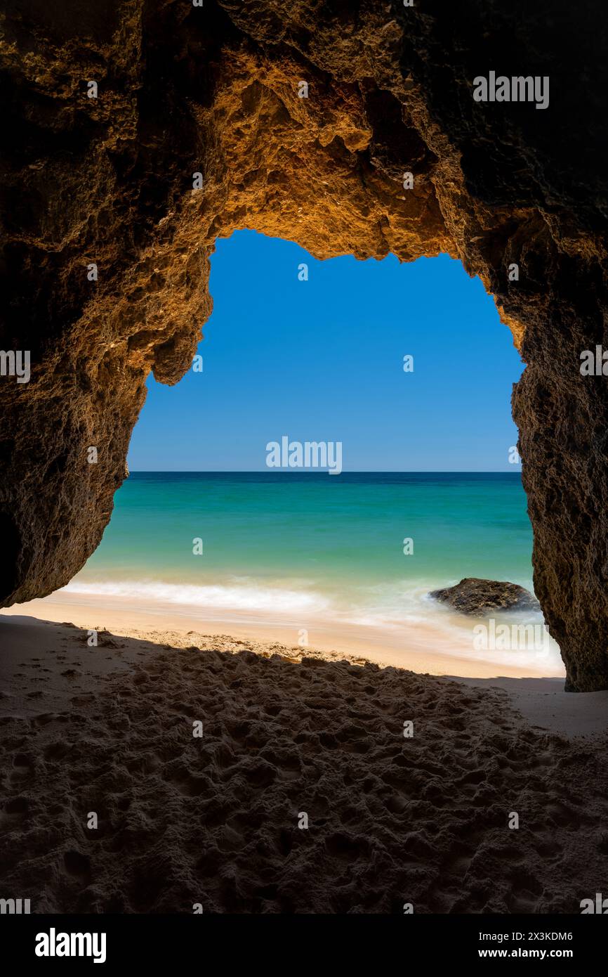 Grotta tipica tra le scogliere rocciose dell'Algarve in Portogallo con ingresso alla spiaggia Foto Stock