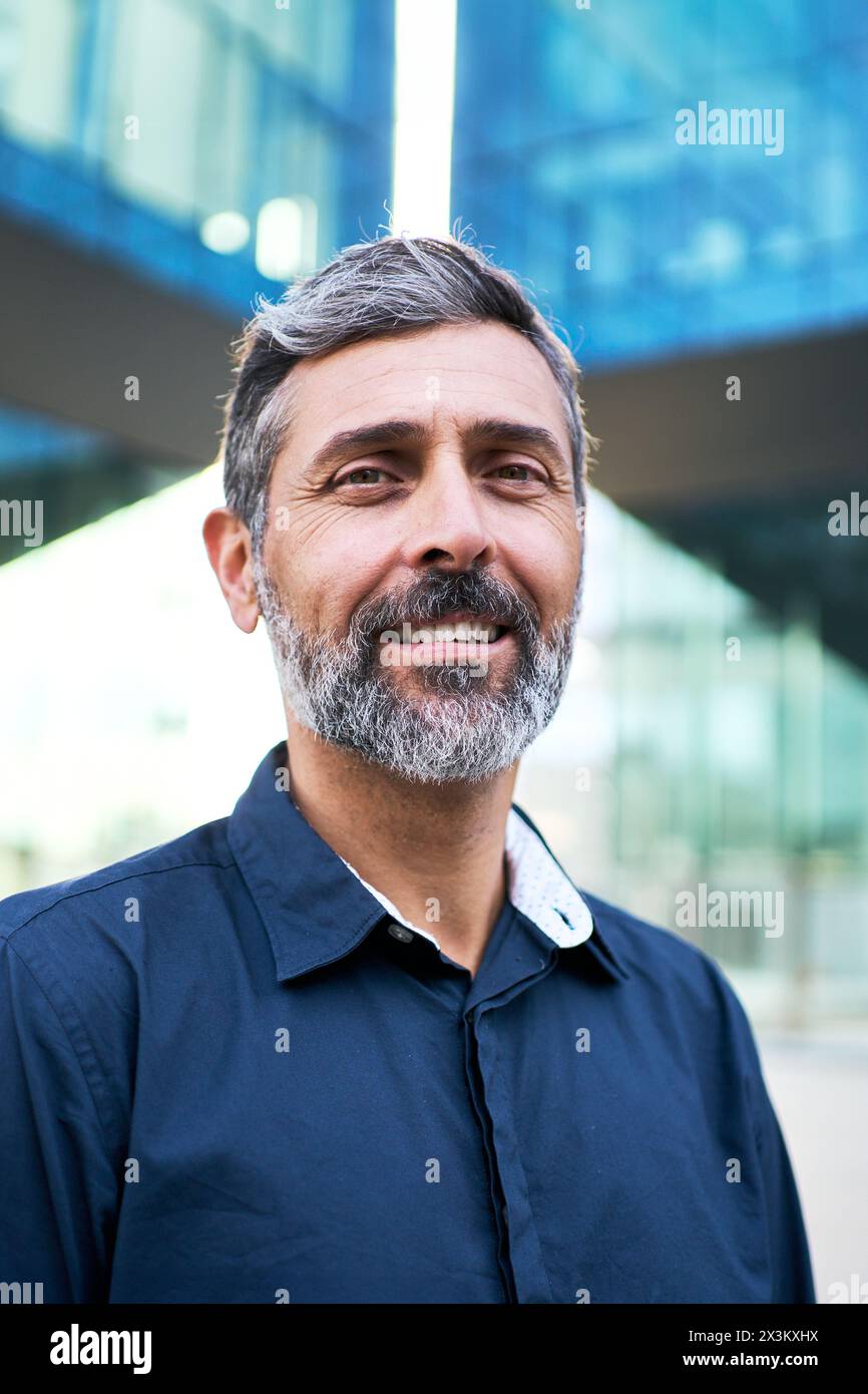 Uomo d'affari maturo dai capelli grigi che sorride alla macchina fotografica con un atteggiamento positivo nella camicia vestito. Foto Stock