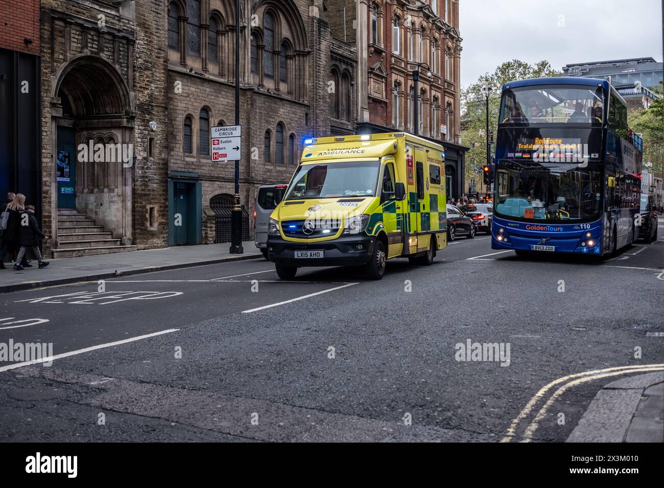 27 aprile 2024, Londra. L'ambulanza sorpassa un autobus a Leicester Square. Foto Stock