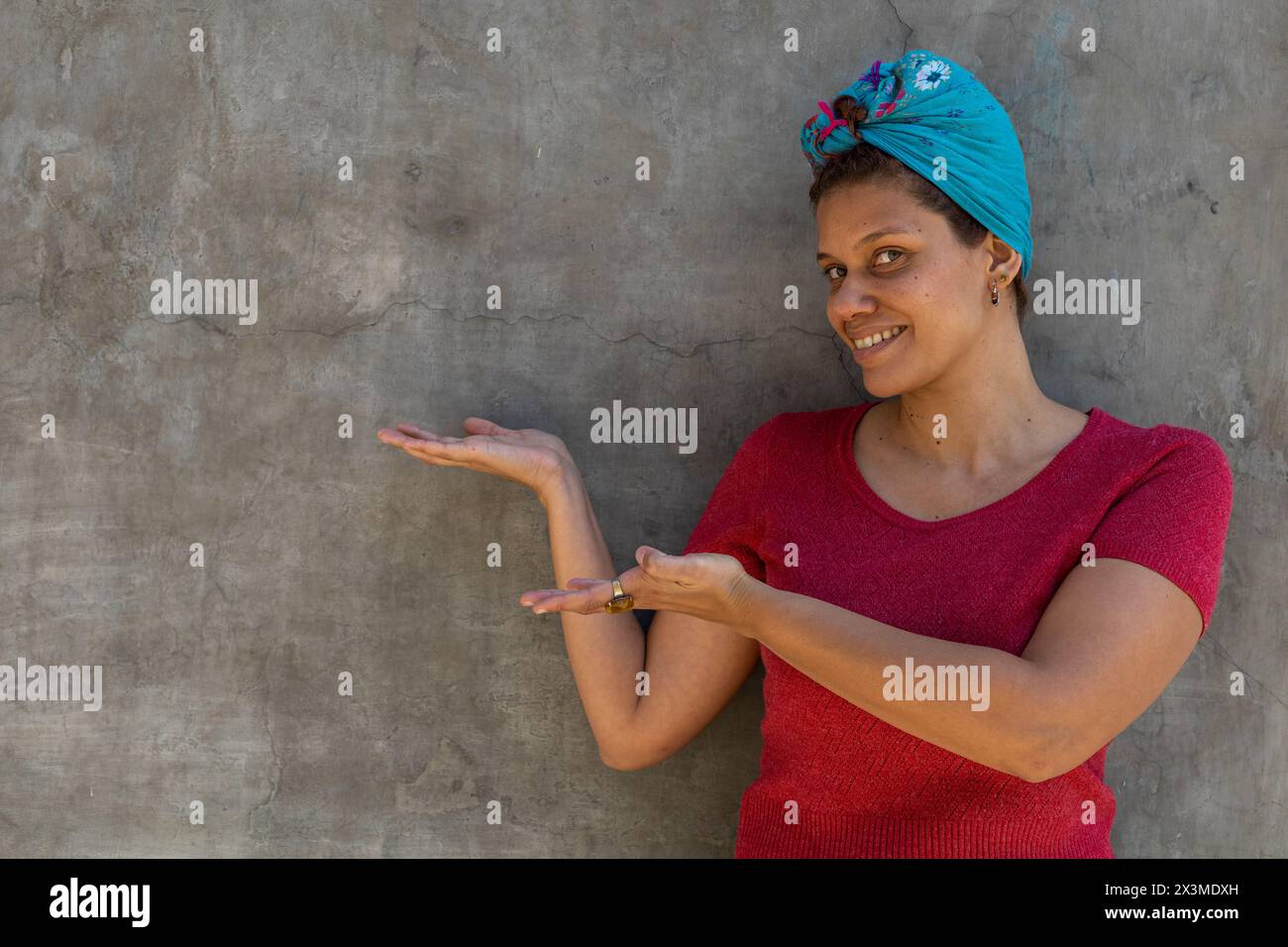 Donna afro latinoamericana sorridente (34) con la sciarpa sulla testa, isolata su sfondo grigio punta con i suoi due cattivi allo spazio vuoto. Promo concept Foto Stock