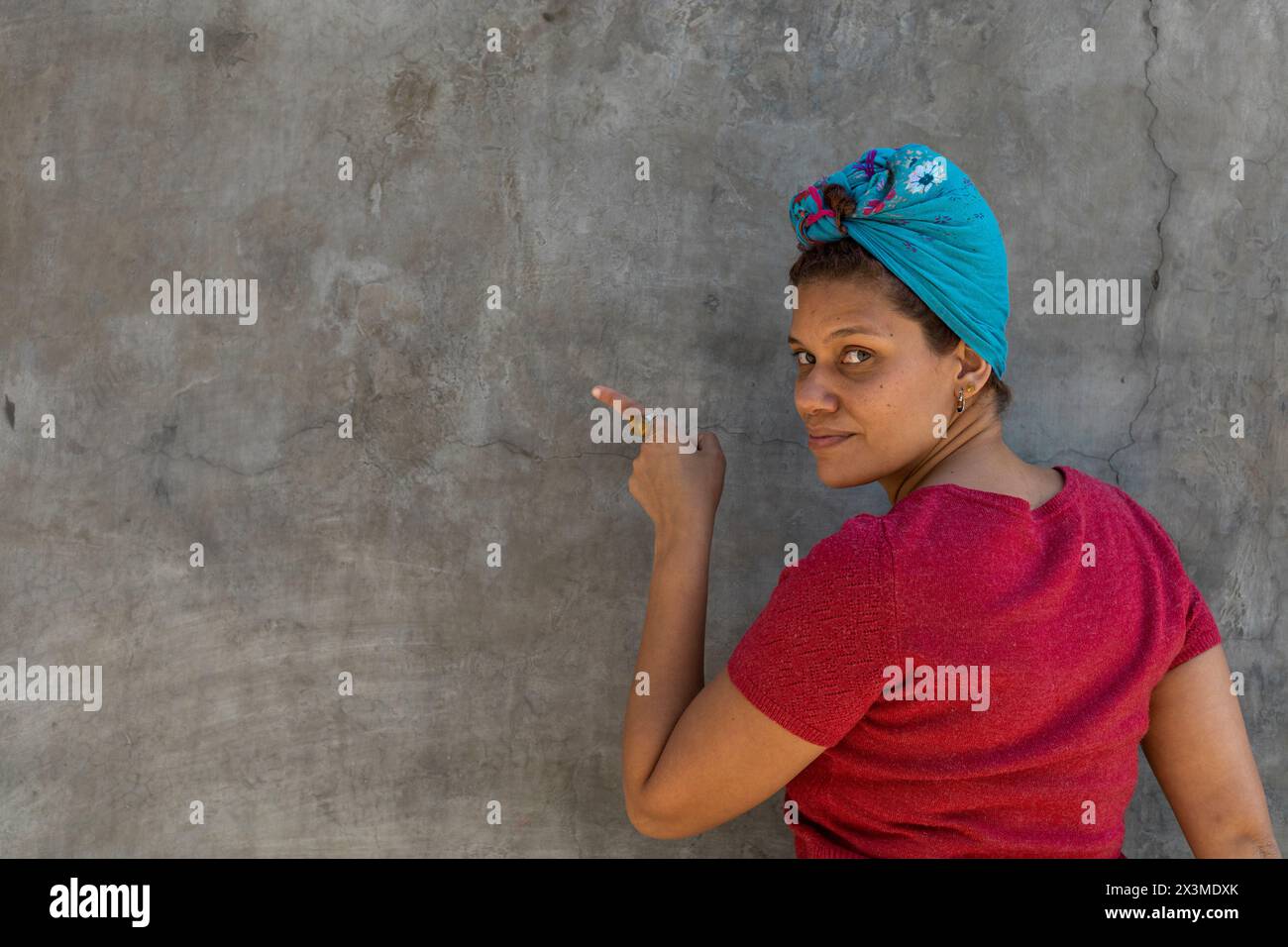Donna afro latinoamericana sorridente (34) con velo, isolata su sfondo grigio punta il dito verso uno spazio vuoto. Offerta promozionale Concept. Foto Stock