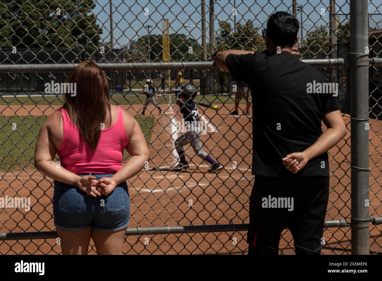 Genitori che guardano il loro bambino giocare a baseball Foto Stock