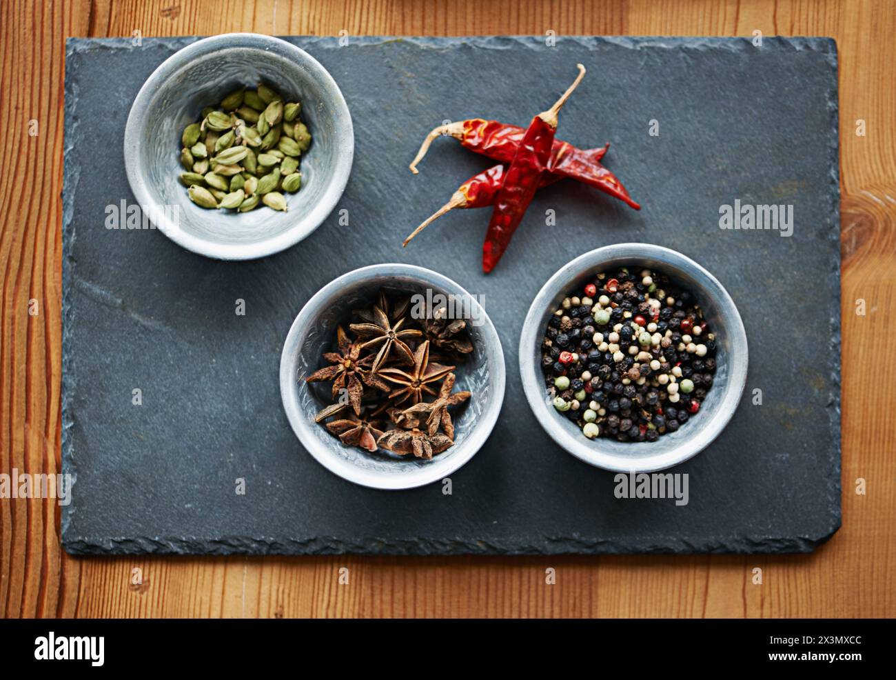 Peperoncini, ingredienti e spezie nella ciotola sopra a bordo per cucinare per la cucina, il pasto e il pranzo. Condimenti, condimenti e pepe essiccato per buongustai Foto Stock