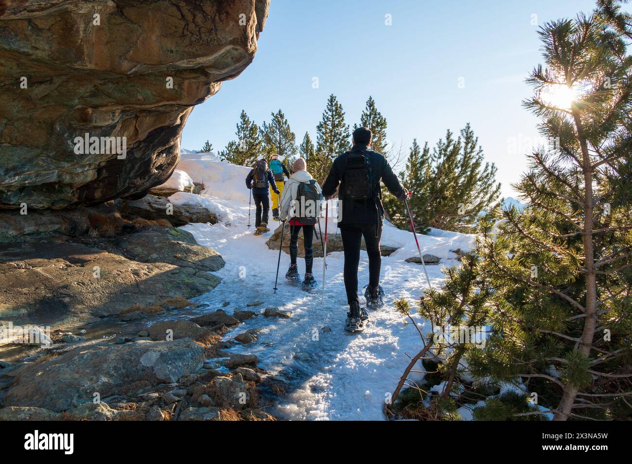 un gruppo di escursionisti attraversa un passaggio roccioso con le racchette da neve Foto Stock