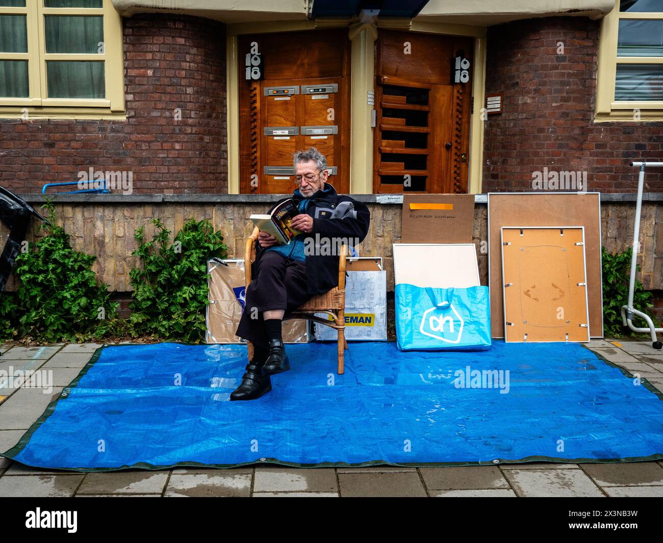 Amsterdam, Paesi Bassi. 27 aprile 2024. Si vede un uomo che aspetta che la pioggia si fermi per mettere le sue cose da vendere. Il King's Day è rinomato per essere uno dei festeggiamenti più grandi e colorati del paese, specialmente ad Amsterdam. La città è piena di arancio, mentre la gente si diverte con la festa di strada più grande dell'anno, godendosi i mercati liberi e divertendosi sulle barche lungo i canali. (Foto di Ana Fernandez/SOPA Images/Sipa USA) credito: SIPA USA/Alamy Live News Foto Stock