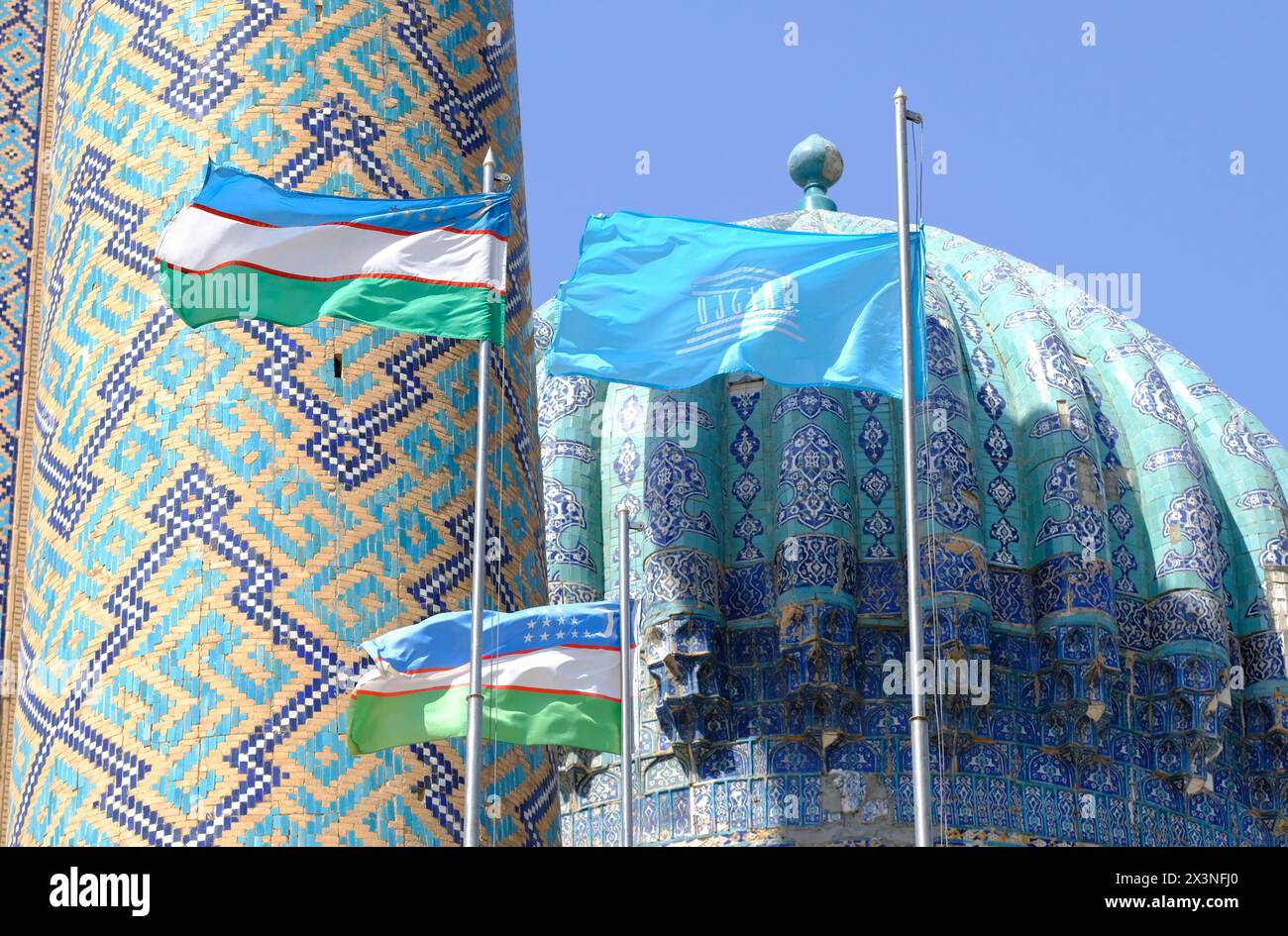 Samarcanda Uzbekistan - le bandiere nazionali dell'Uzbekistan e l'organizzazione dell'UNESCO sorvolano lo storico complesso del Registan nell'agosto 2022 Foto Stock