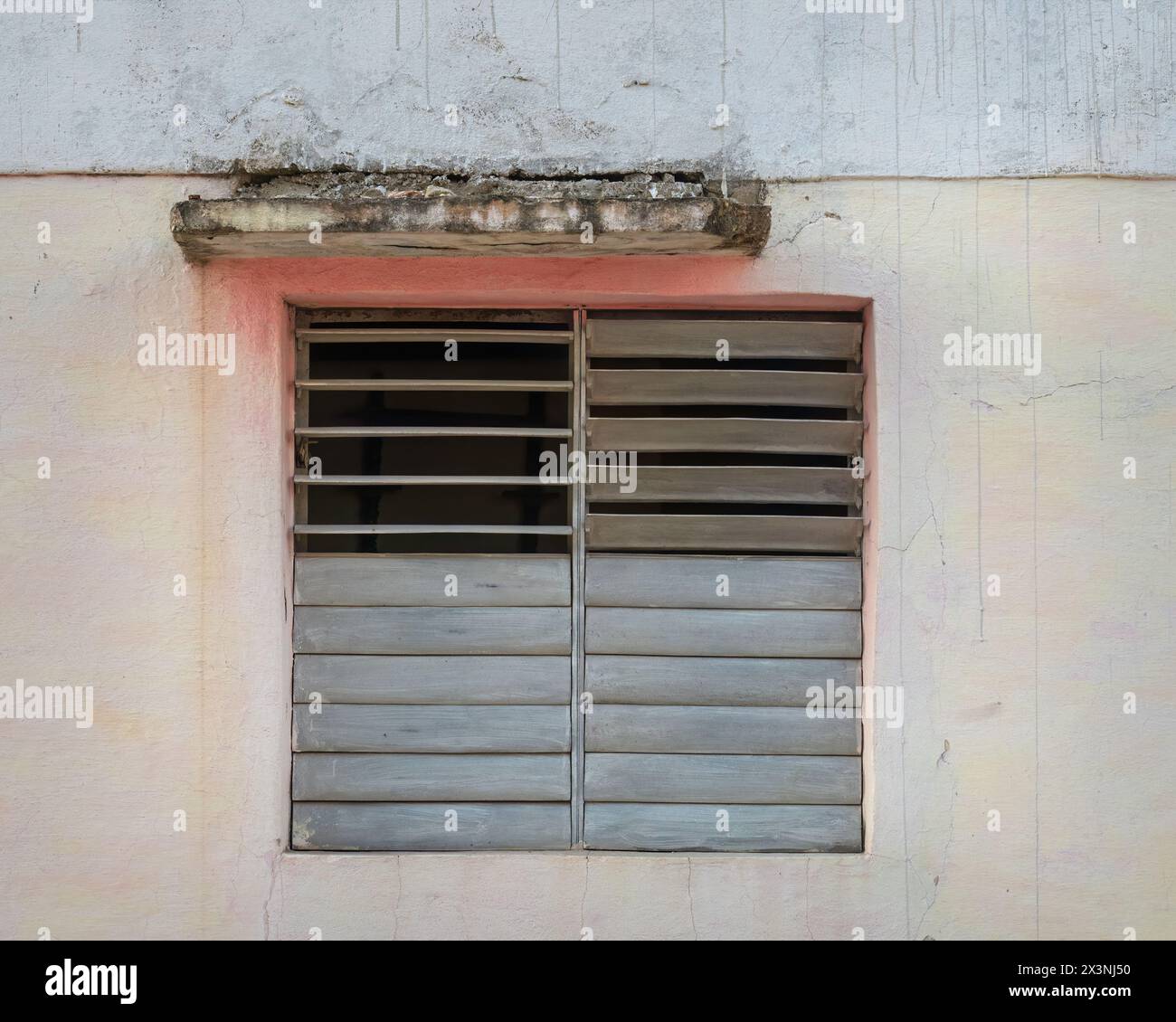 Persiane in legno parzialmente aperte in una finestra di una proprietà nelle strade secondarie della città Vecchia, Trinidad, Cuba. Foto Stock