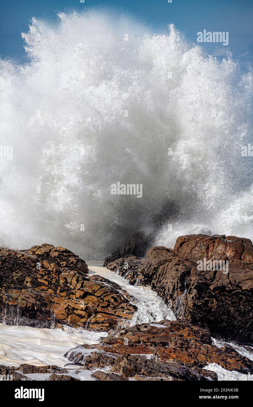 Una grande onda oceanica si tuffa in una giornata tempestosa ma soleggiata. Costa rocciosa portoghese settentrionale. Foto Stock