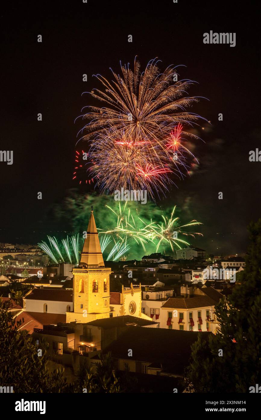 Fuochi d'artificio notturni alla Festa dos Tabuleiros a Tomar, Portogallo, con la torre della chiesa di São João Baptista sotto i riflettori. Foto Stock