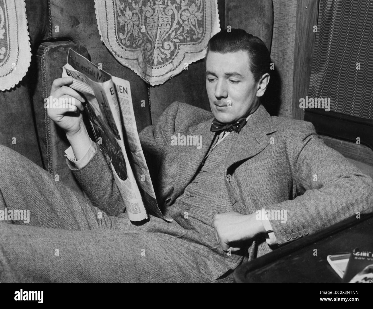 MICHAEL REDGRAVE si rilassa sul set agli Islington Studios durante le riprese di THE LADY VANISHES 1938 regista ALFRED HITCHCOCK Story ETHEL LINA sceneggiatura BIANCA FRANK LAUNDER e SIDNEY GILLIAT Gainsborough Pictures / Metro Goldwyn Mayer Foto Stock