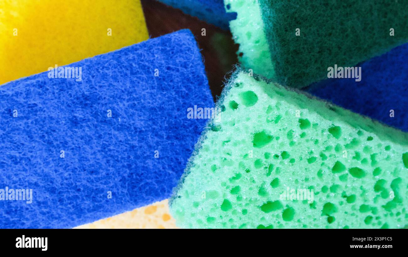 Ausili per la pulizia colorati. Una pila di spugne blu, verdi e gialle. Usi per cataloghi di prodotti per la pulizia, guide per la casa. Foto Stock