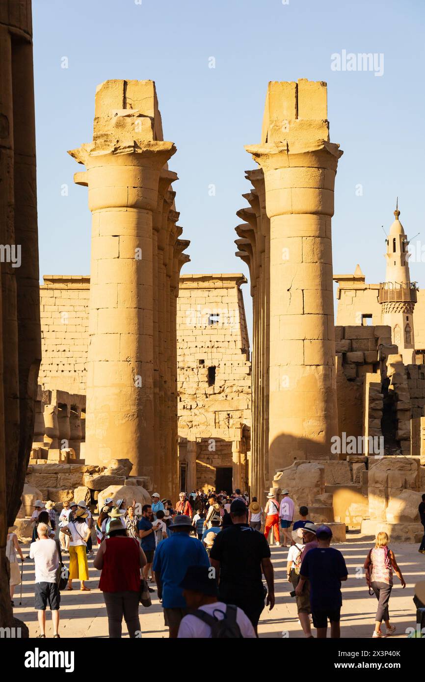 I turisti camminano attraverso il Grand Colonnato di colonne verso il pilone, il tempio di Luxor, Luxor, Egitto Foto Stock