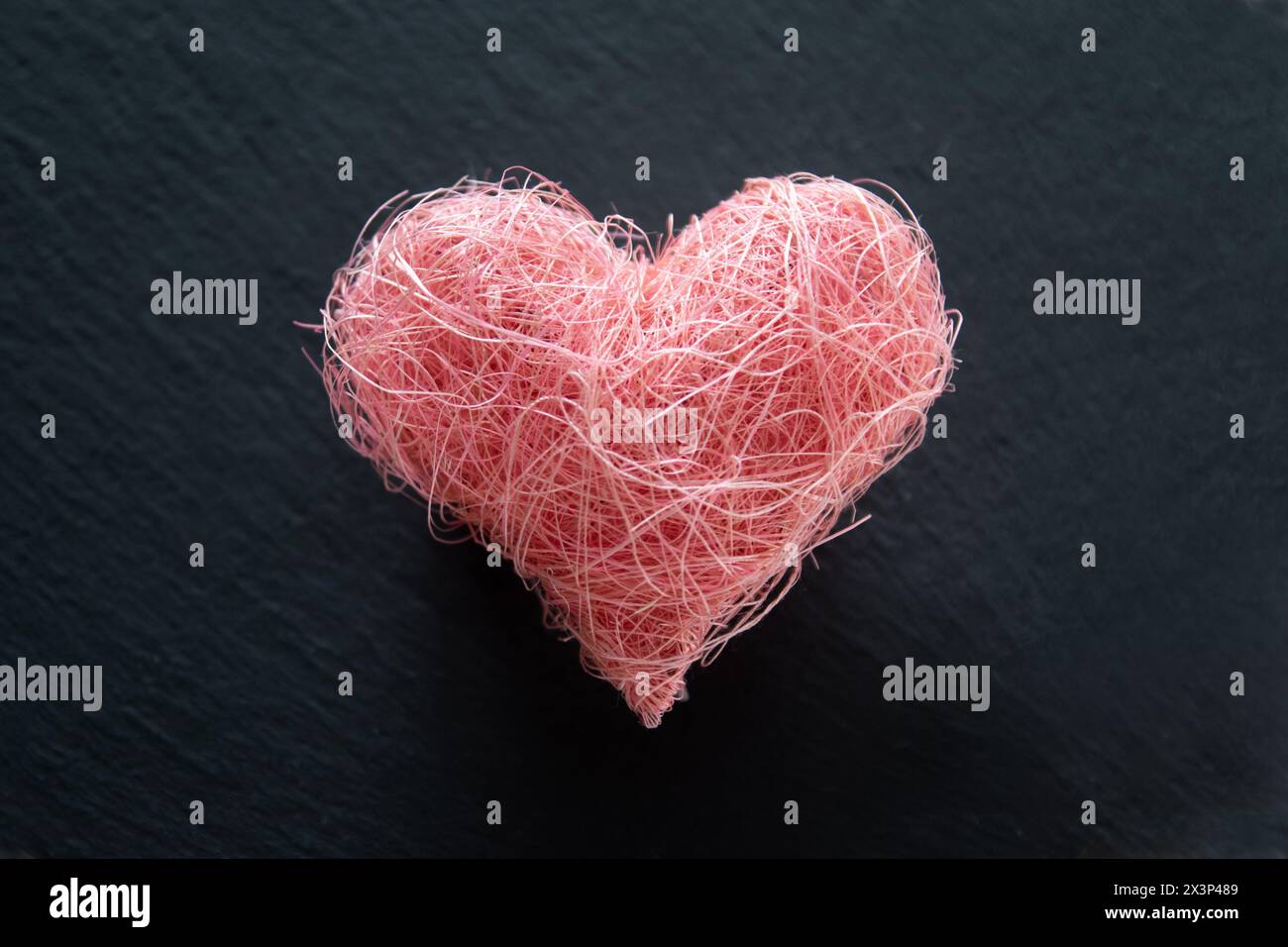 Forma a cuore realizzata in tessuto di materiale su sfondo nero con copyspace. Concetto di San Valentino e amore romantico. Foto Stock