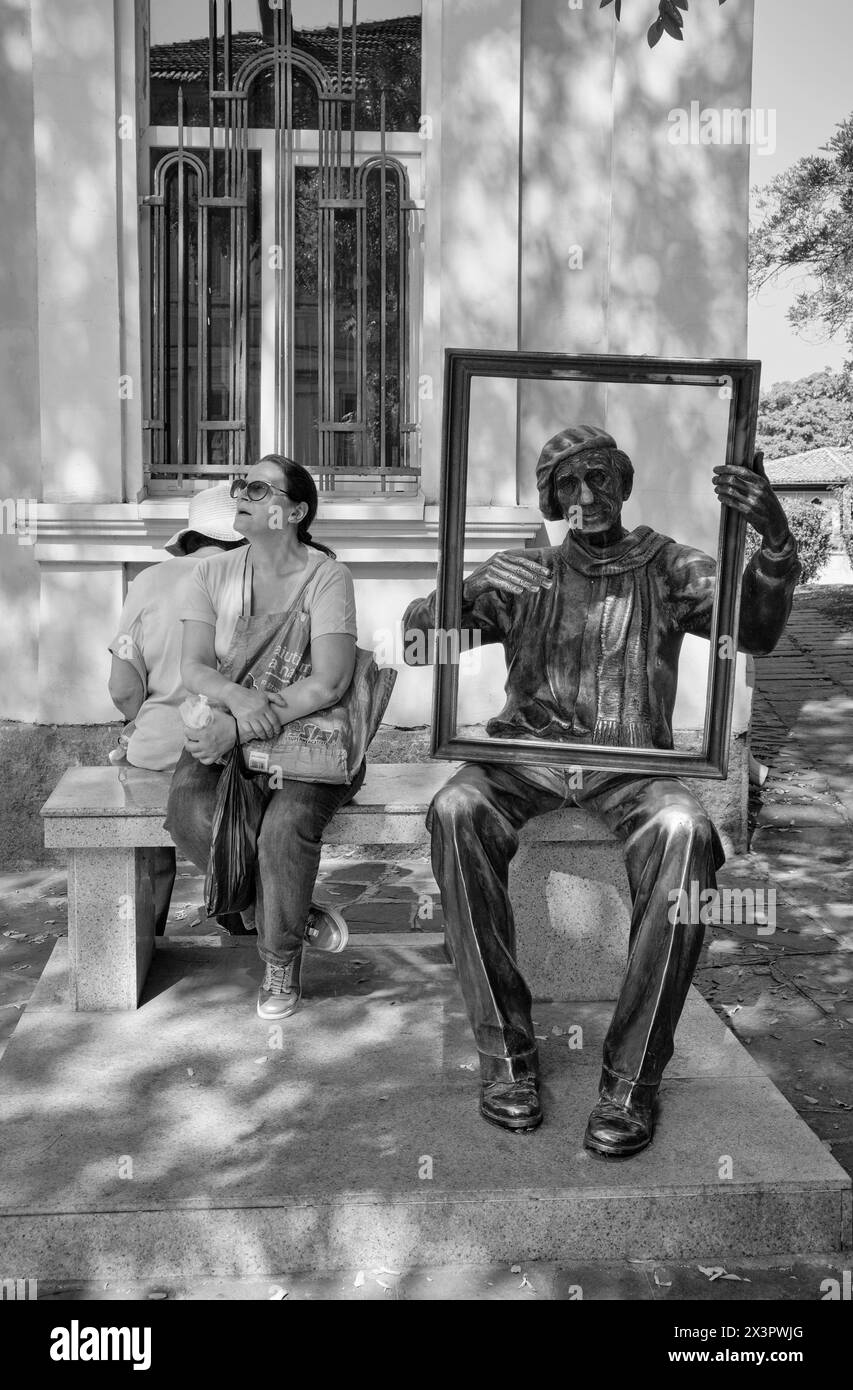 Bulgaria, Plovdiv; 23 settembre 2023, persone che riposano e una statua di bronzo su una panchina in una strada centrale della città - EDITORIALE Foto Stock