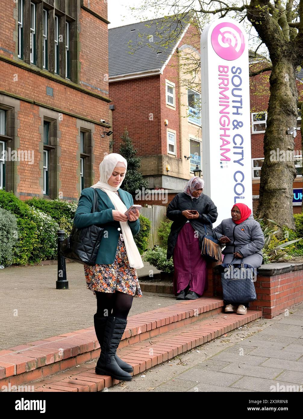 Donne che guardano i loro smartphone fuori dal South & City College Birmingham - Handsworth Foto Stock