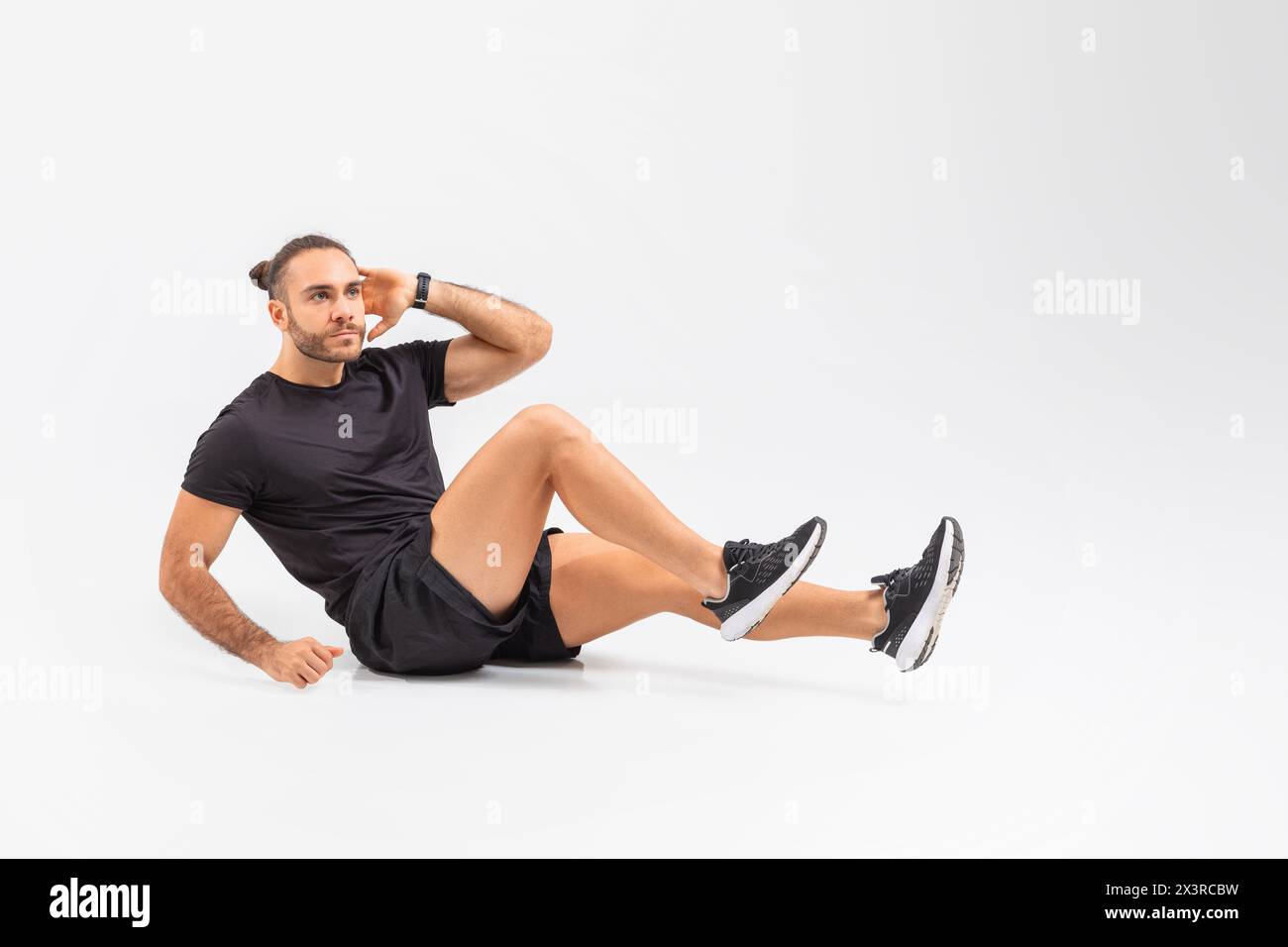 Uomo seduto a terra con camicia e shorts neri Foto Stock