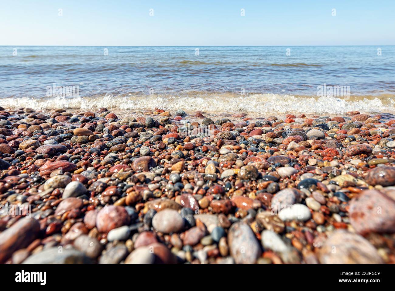 Onde in mare vicino alla costa su una spiaggia di ciottoli vuota. Mare e spiaggia. Vista panoramica sulla costa dell'oceano. Foto Stock