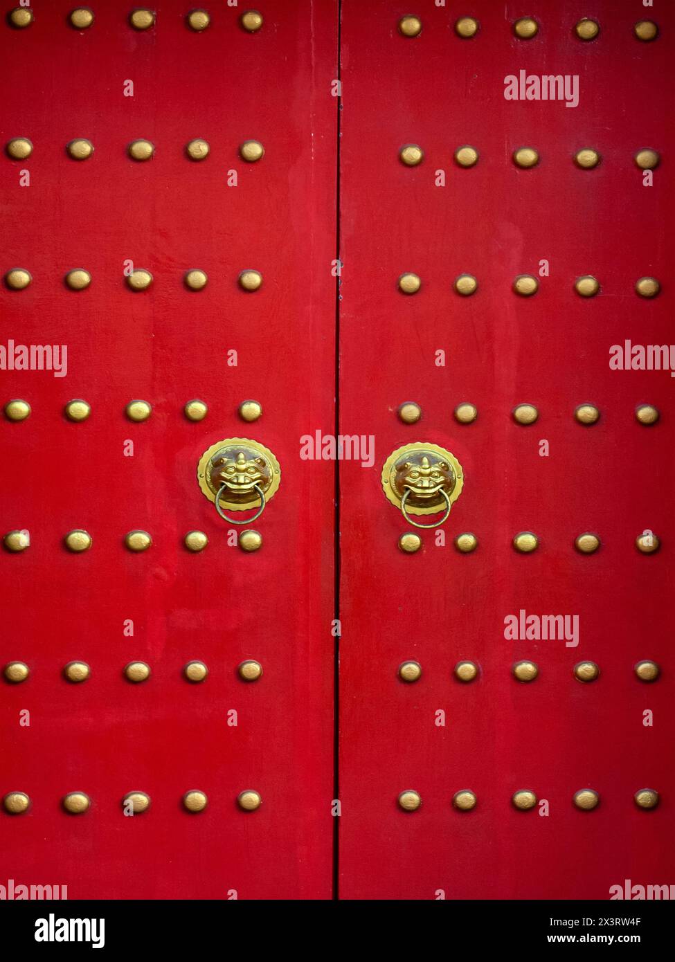 Porta rossa con teste di leone in stile asiatico. Porte in legno rosso con dettagli dorati. Foto Stock