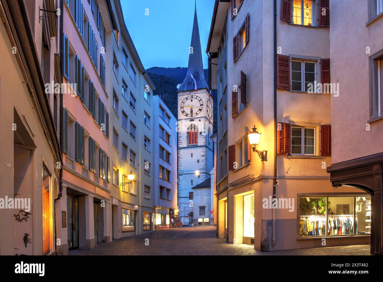 Scena notturna lungo la via Obere nel centro storico di Coira, Grigioni, Svizzera, con l'imponente torre di San Chiesa di Martin Foto Stock