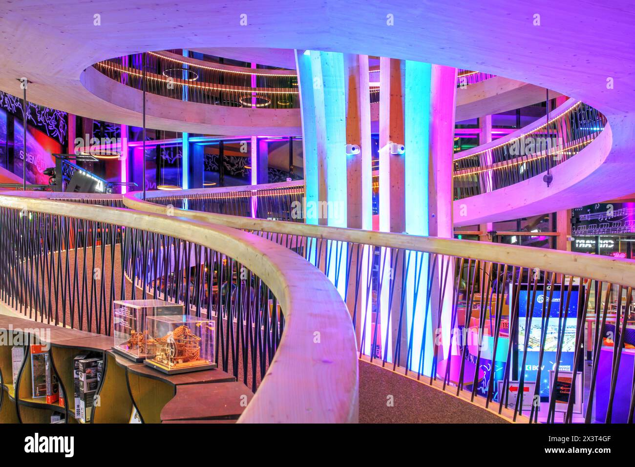Una splendida stalla a spirale in legno nell'atrio principale dell'Exploreit Y-Parc Technopole a Yverdon-les-Bains, Svizzera, fotografata illuminata di notte. Foto Stock