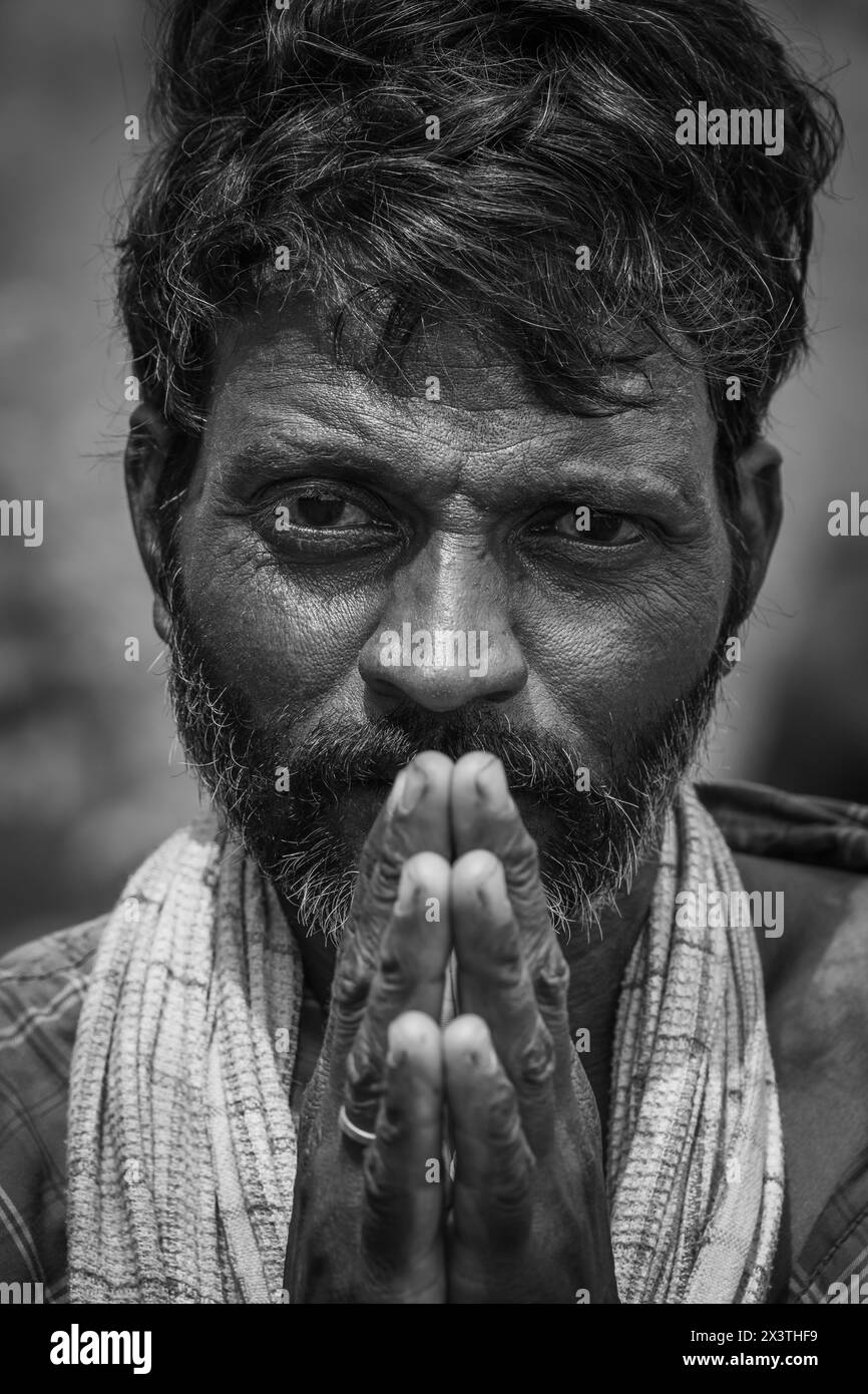 Il ritratto di un pastore indiano con le mani fa un gesto di namaste con le mani unite davanti. Uomo con le mani agganciate davanti alla bocca, che guarda Foto Stock