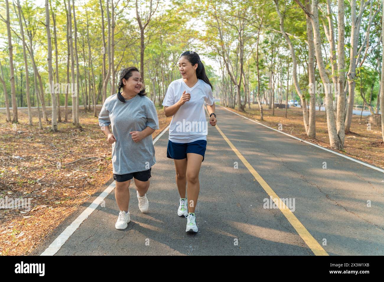 Due amiche asiatiche felici che corrono insieme la mattina in un parco di corsa in un giorno d'estate Foto Stock