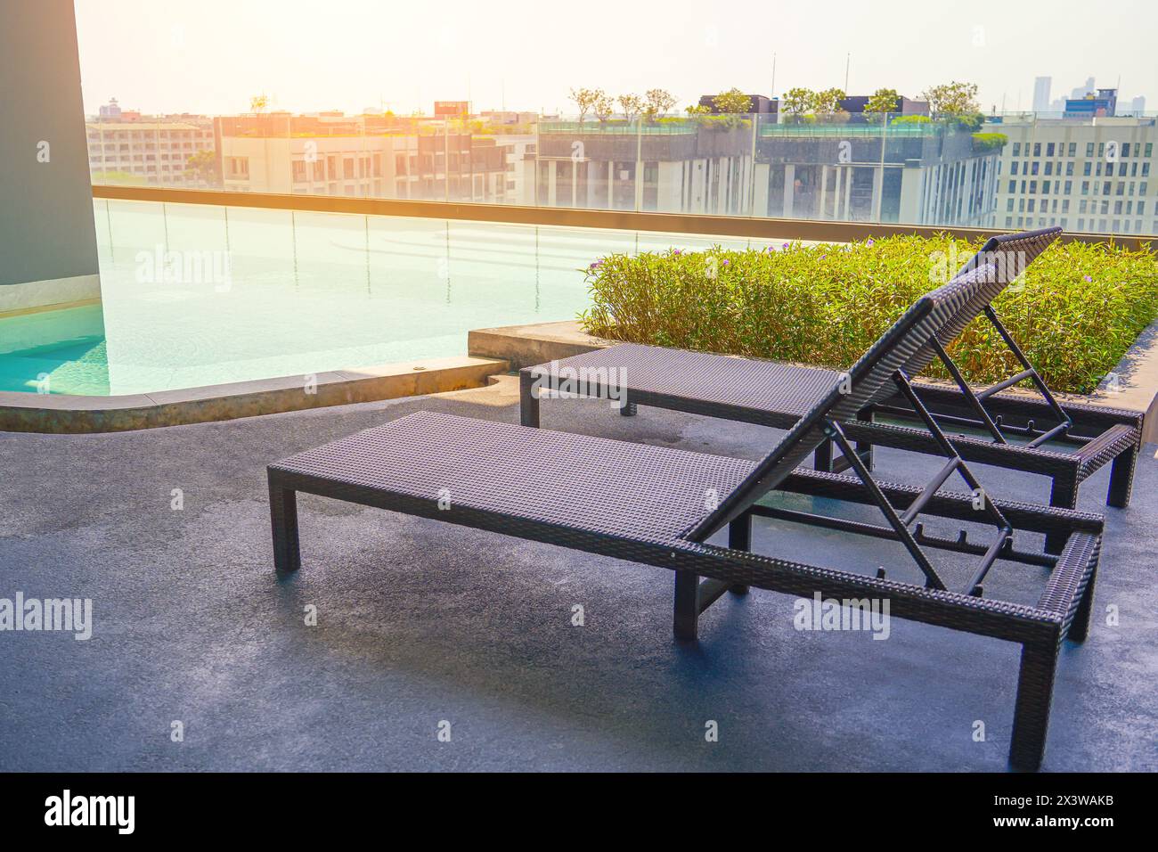 Scenario di un'area relax moderna, piscina, chaise lounge e condominio nel centro cittadino. Foto Stock