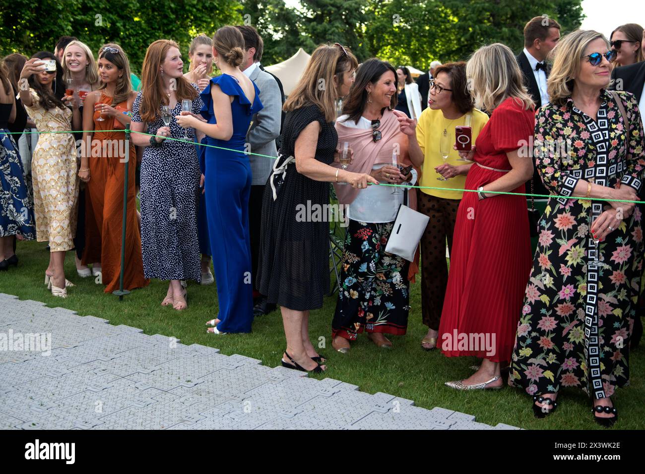 Donne ricche e ricche Regno Unito anni '2020 L'Hurlingham Club è un esclusivo social privato nella zona di Fulham a Londra. L'annuale festa estiva in giardino - Fête Champête, dove i membri mettono in mostra le loro auto d'epoca e d'epoca nel Concourse d'Elégance; le auto vengono guidate nei terreni del club. Le signore chiacchierano in attesa che la prossima auto passasse. Londra, Inghilterra 11 giugno 2022 UK 2020s HOMER SYKES Foto Stock