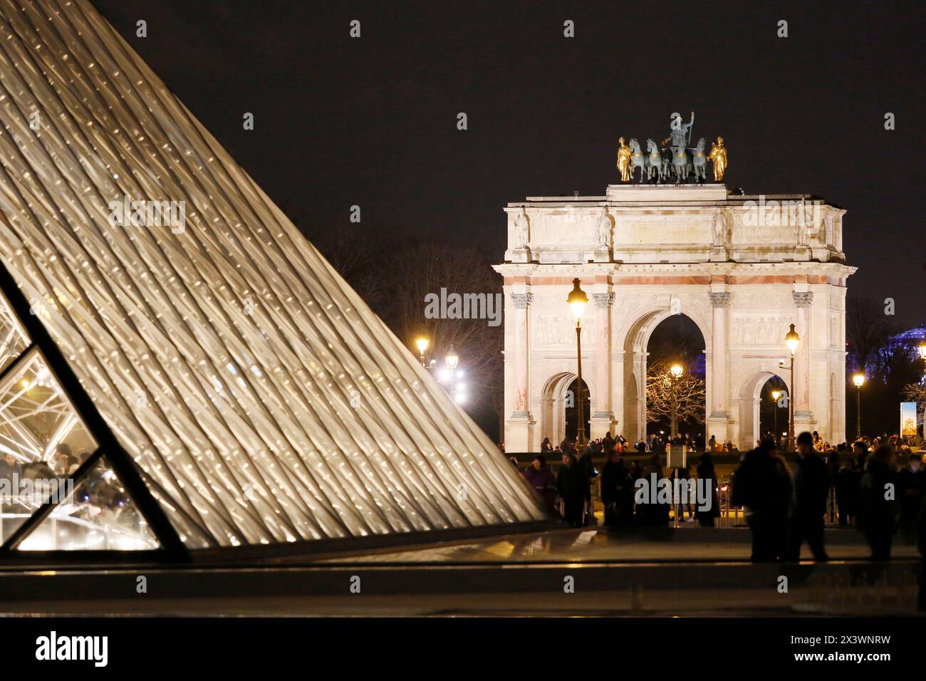 Parigi. 1° distretto. Museo del Louvre di notte. In primo piano si trova la piramide (architetto: Ieoh Ming Pei). Sullo sfondo, l'arco trionfale del Foto Stock