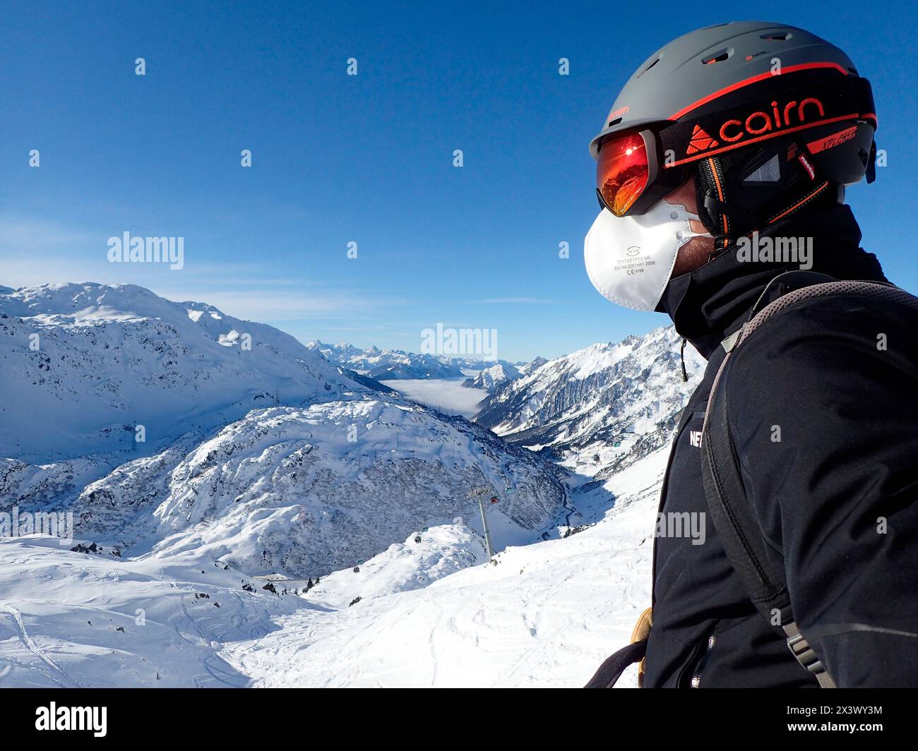 Austria, Tirolo, Sankt Anton am Arlberg , un uomo indossa un casco da sci, occhiali da sole e una maschera anti covid FFP2 Foto Stock