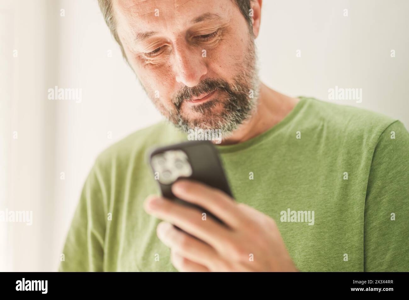 Man ha ricevuto un messaggio di testo o un'e-mail soddisfacente sullo smartphone, attenzione selettiva Foto Stock