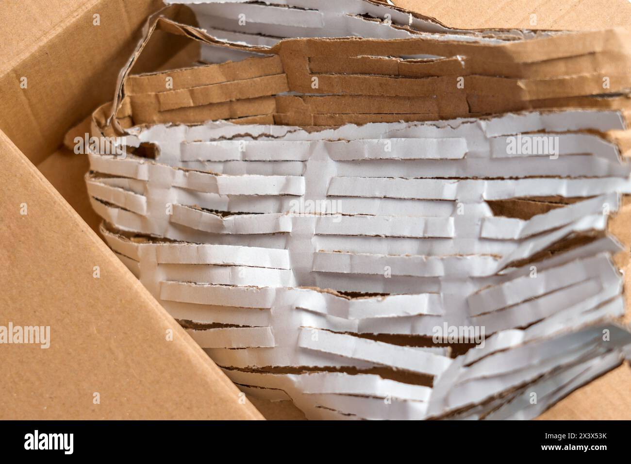 Scatola di cartone piena di carta da imballaggio tagliata per la protezione dei pacchi. Foto Stock