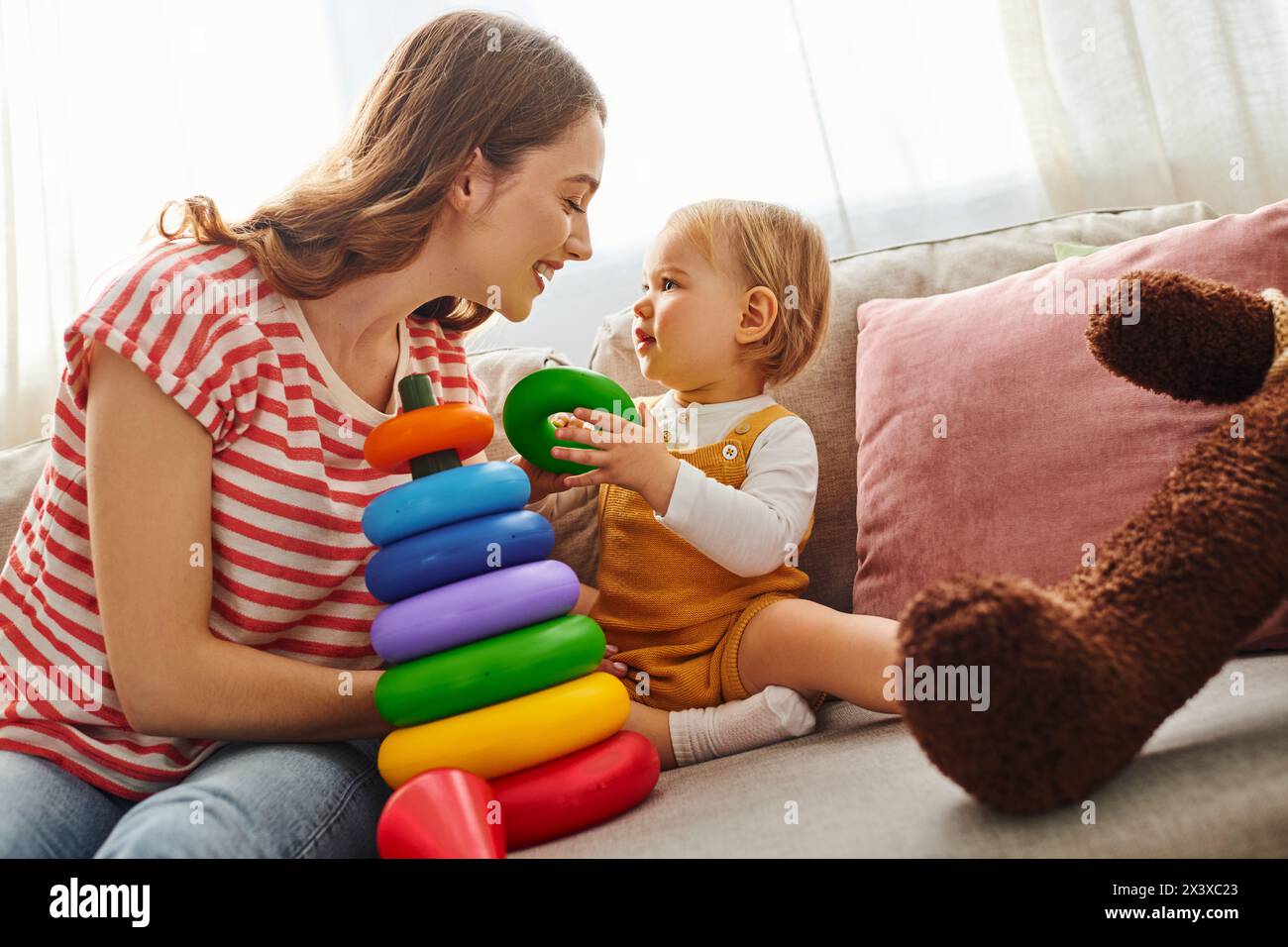 Una giovane madre giocherellando con la figlia su un comodo divano di casa. Foto Stock