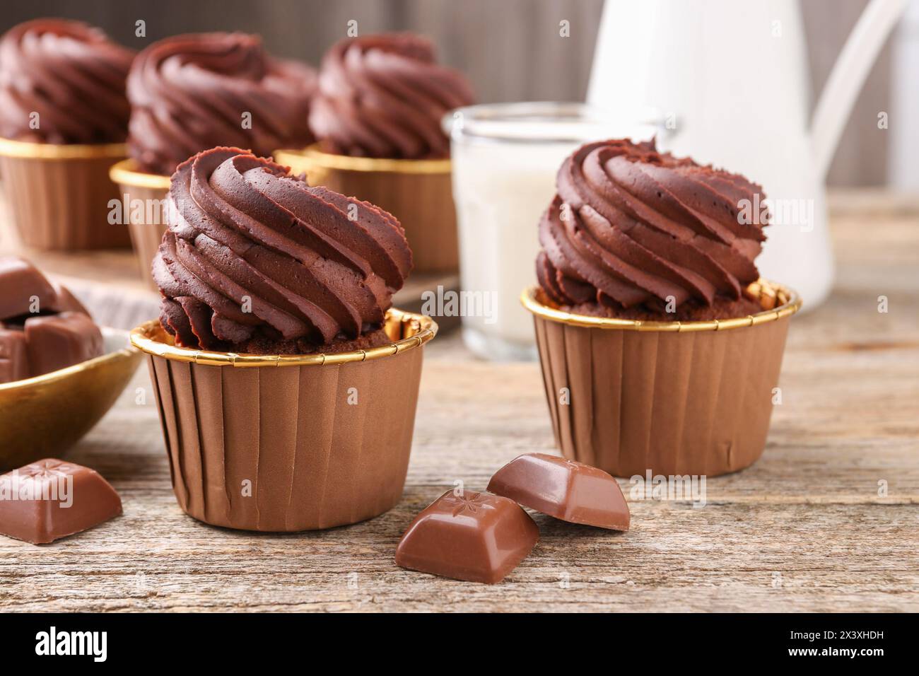 Deliziosi cupcake e pezzi di cioccolato su un tavolo di legno, primo piano Foto Stock