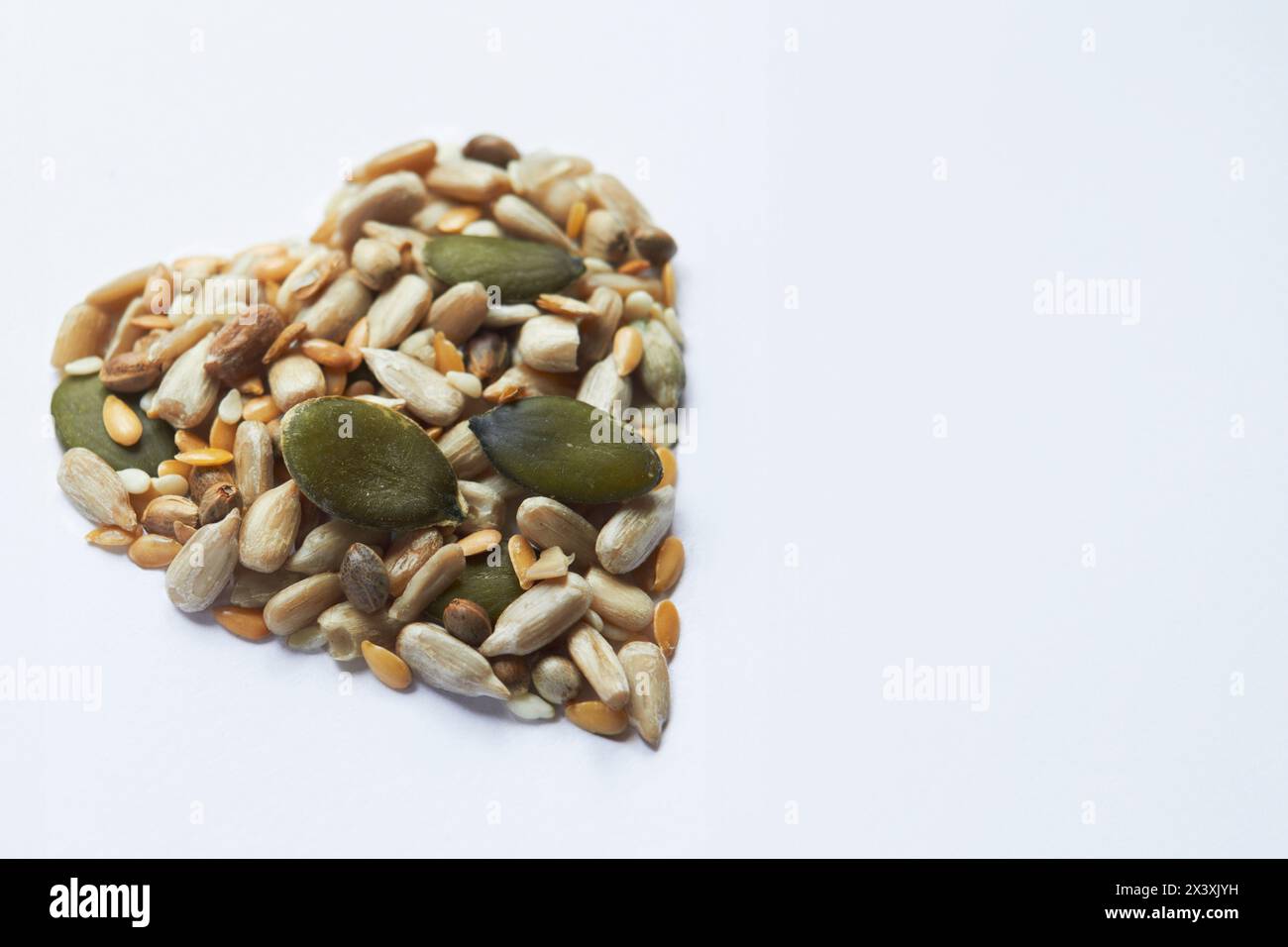 Shot salutare con noci e semi a forma di cuore su sfondo bianco Foto Stock
